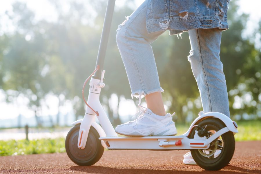 Legs of woman riding electric kick scooter. Ecological transportation concept.